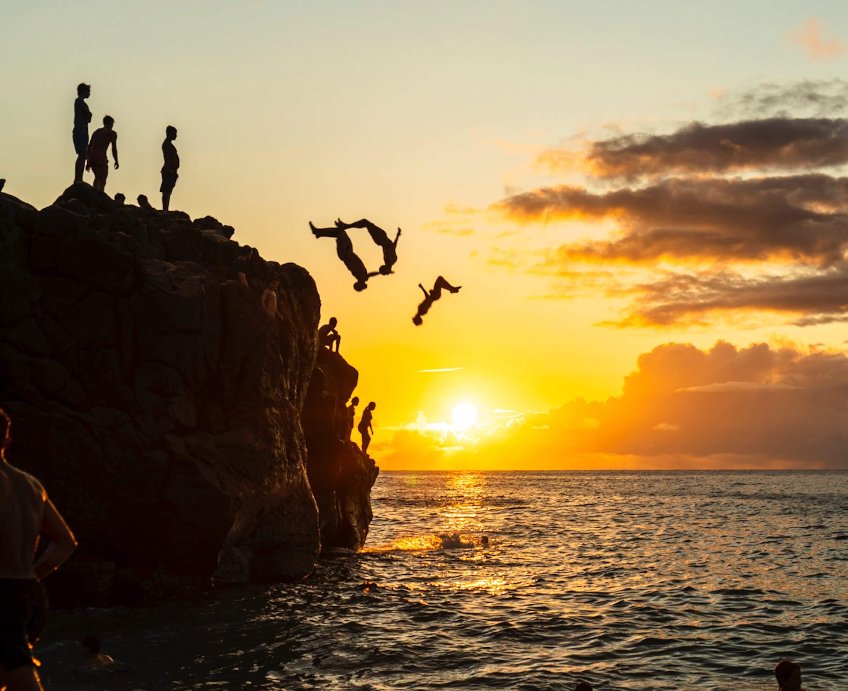 People jumping off of a cliff into water